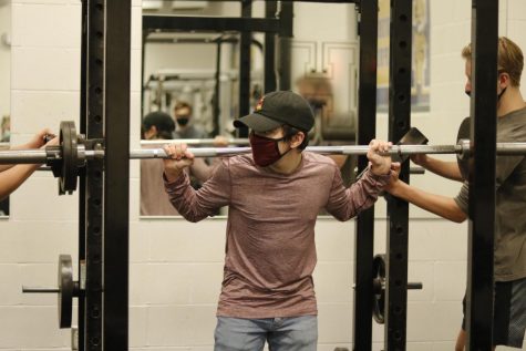 Nov. 24, junior Aidan Ferrar squats 85 pounds with the assist of his classmates Nov. 23. Weight training has left me feeling more and more confident lately and Im feeling better than ever. Its a fun environment with little judgement, Ferrar said.