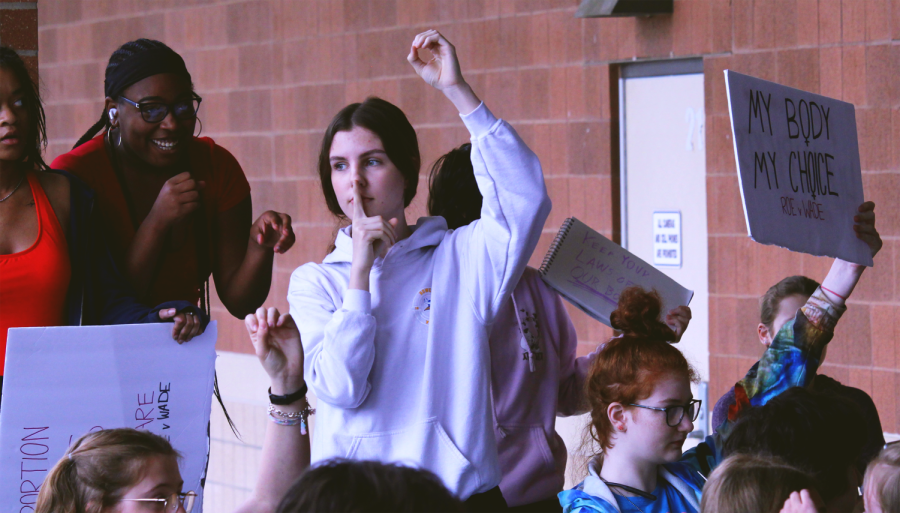 In attempt to silence the crowd, junior Kate Foster holds up her hand so the speakers can begin their speeches. 