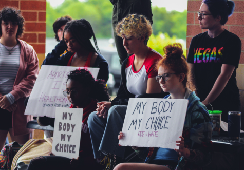 The crowd sits in support of the student speakers while holding signs quietly during the Womens Rights Rally, May 25.
