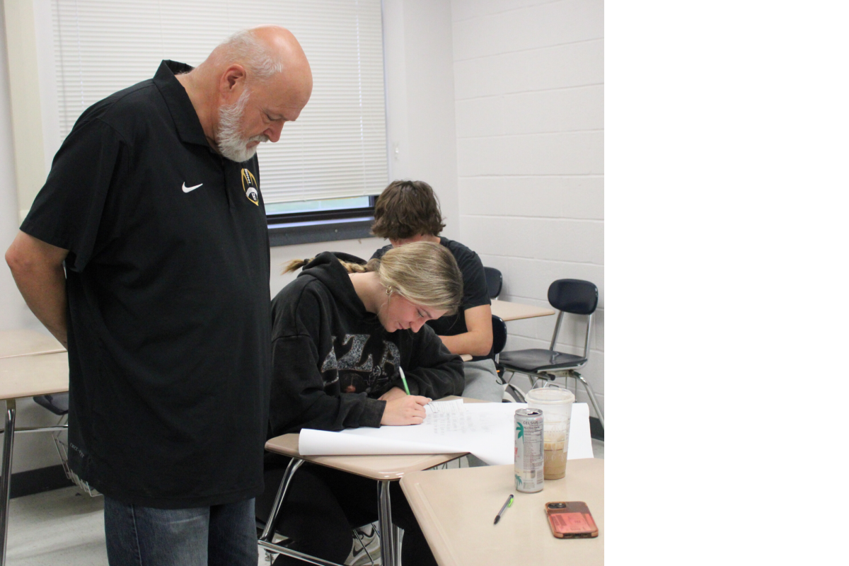 A Helping Hand – Social studies teacher Eric West helps sophomore McKinnon Rivers with her poster for World History, Nov. 13. 